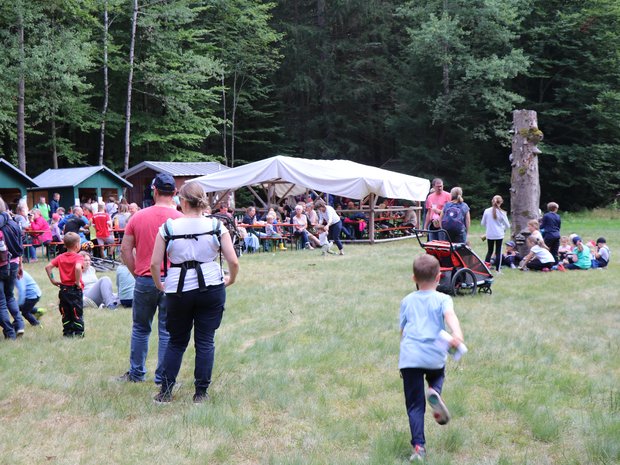 Auf einer Wiese findet ein sogenanntes Spechtfest statt, Erwachsene und Kinder spielen Spiele im Freien