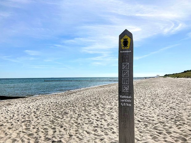 Ein Wegweiser mit der Schrift "Nationalpark" steht am Strand des Wattenmeers. 