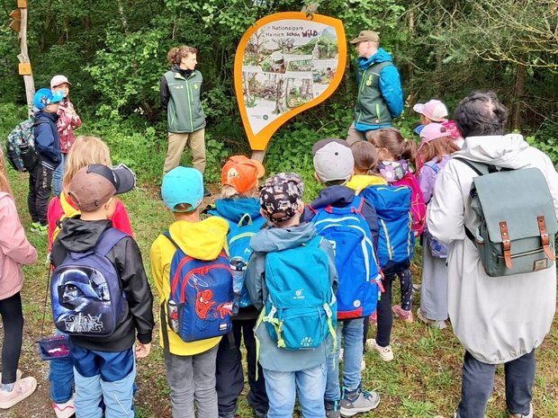 Eine Gruppe an Kindern bekommt das Comic über die Katze Wilma von Benny und einer Forschungspraktikantin vorgelesen. 
