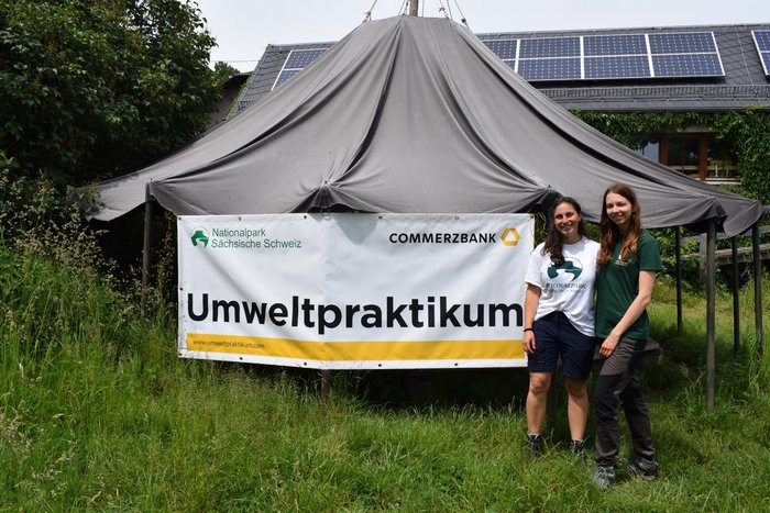 Zwei junge Menschen stehen zusammen neben dem Commerzbank-Umweltpraktikum-Banner.