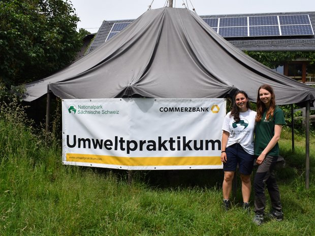 Zwei junge Menschen stehen zusammen neben dem Commerzbank-Umweltpraktikum-Banner.