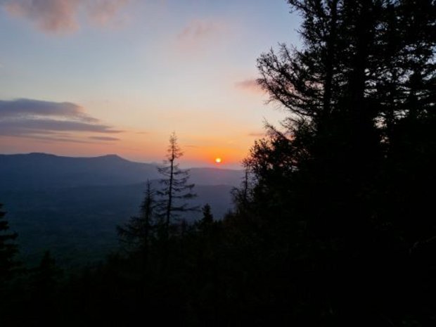 Blick über die Berggipfel aus deinem Waldgebiet mit Sonnenuntergang am Horizont