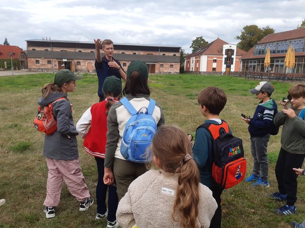 Eine Gruppe Kinder steht mit Lupen auf einer Wiese