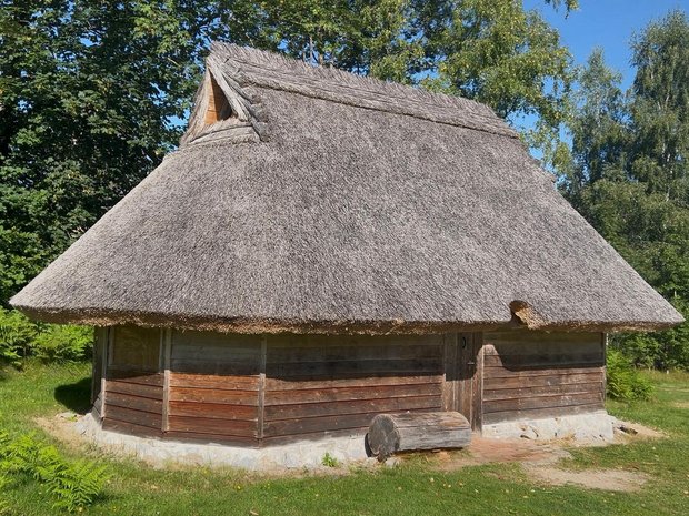 Außenaufnahme einer Reet-gedeckten Holzhütte mit Spitzdach.