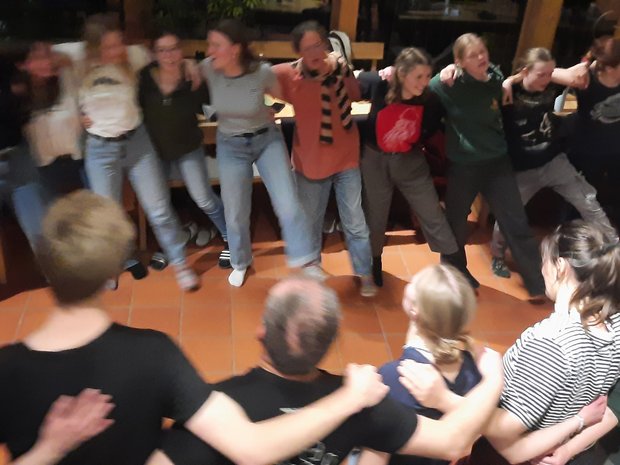 Gruppe Menschen steht Arm im Arm im Kreis und schunkelt zur Musik.